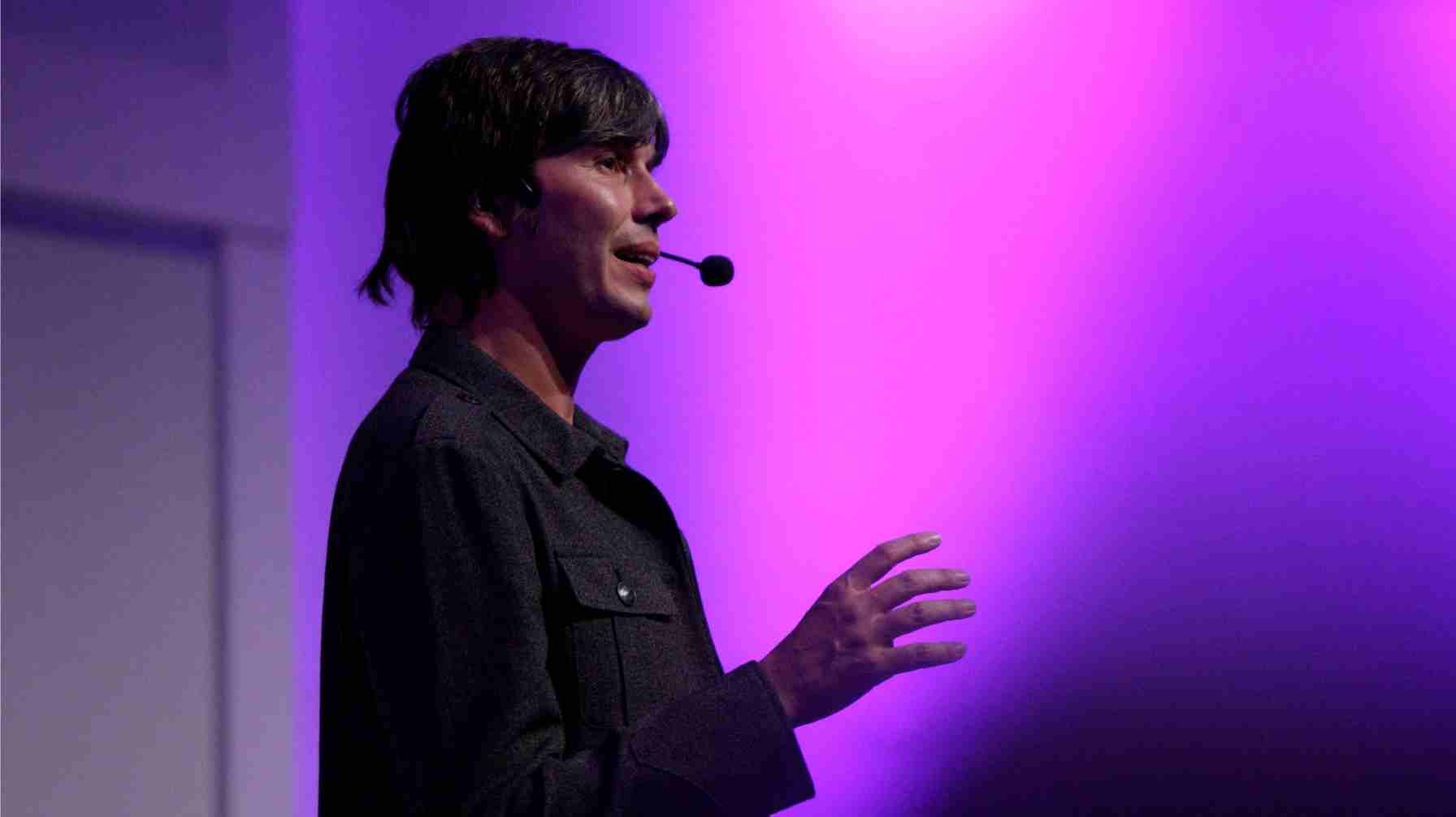 Professor Brian Cox speaking confidently, wearing a headset microphone.
