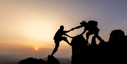 Two climbers, one helping the other indicating leadership.