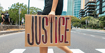 A person walking with a sign saying justice.