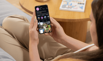 A woman looking at her phone, on the UCIL Instagram feed.