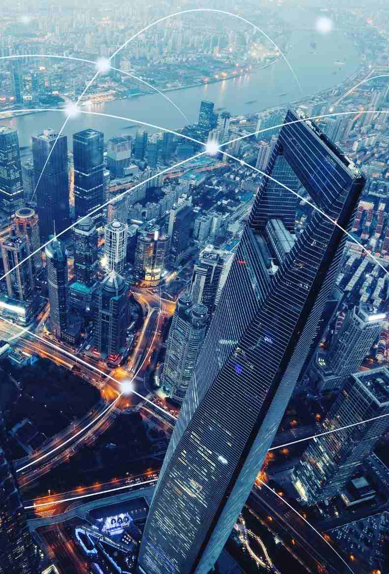 Aerial view of a modern city at night with glowing lights and a network of connections overlaid