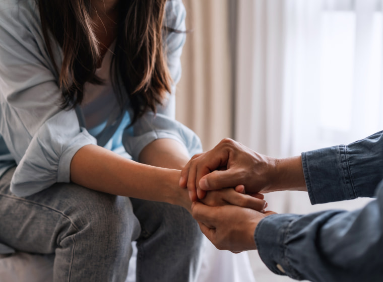 Two people holding hands in support of each other. 